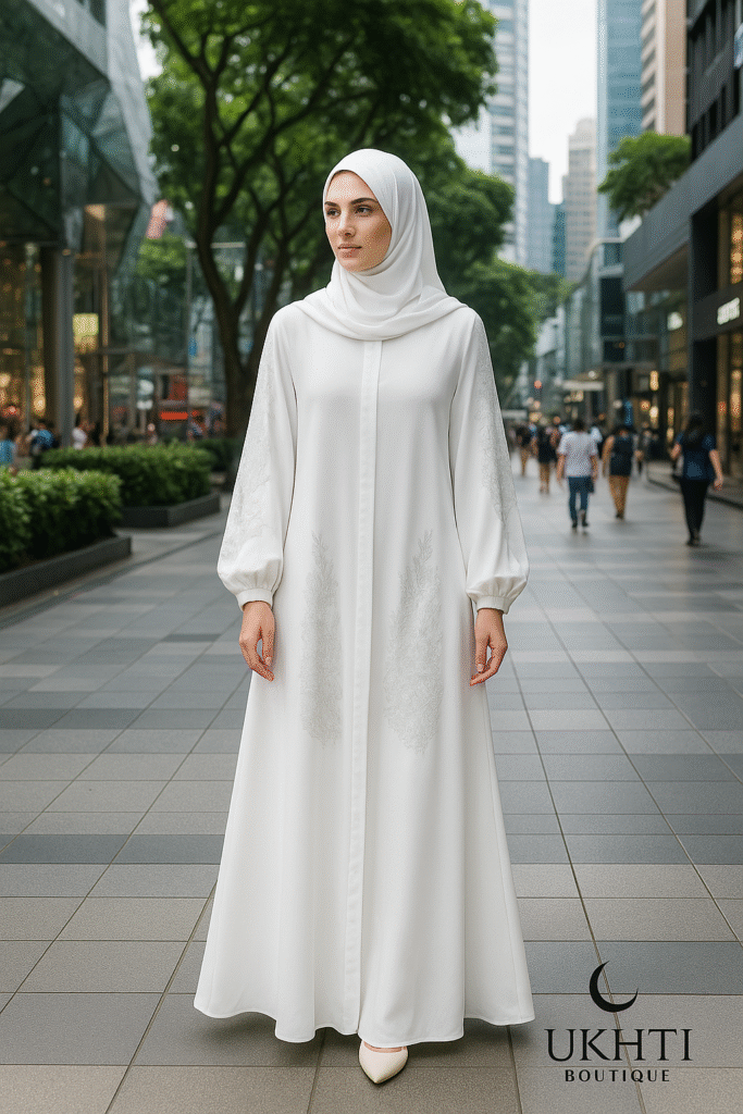 A fair-skinned woman wearing the flowing white abaya with silver embroidery and a matching hijab
Distinctive Orchard Road pedestrian mall with lush greenery and high-end storefronts